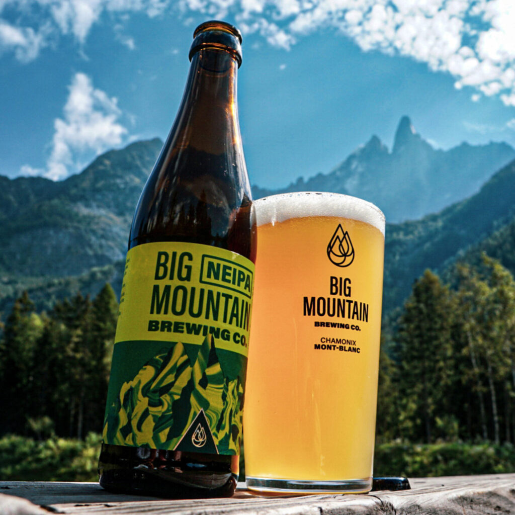NEIPA de la brasserie artisanale Big Mountain Brewing Company par adopte un brasseur avec verre de bière et montagne